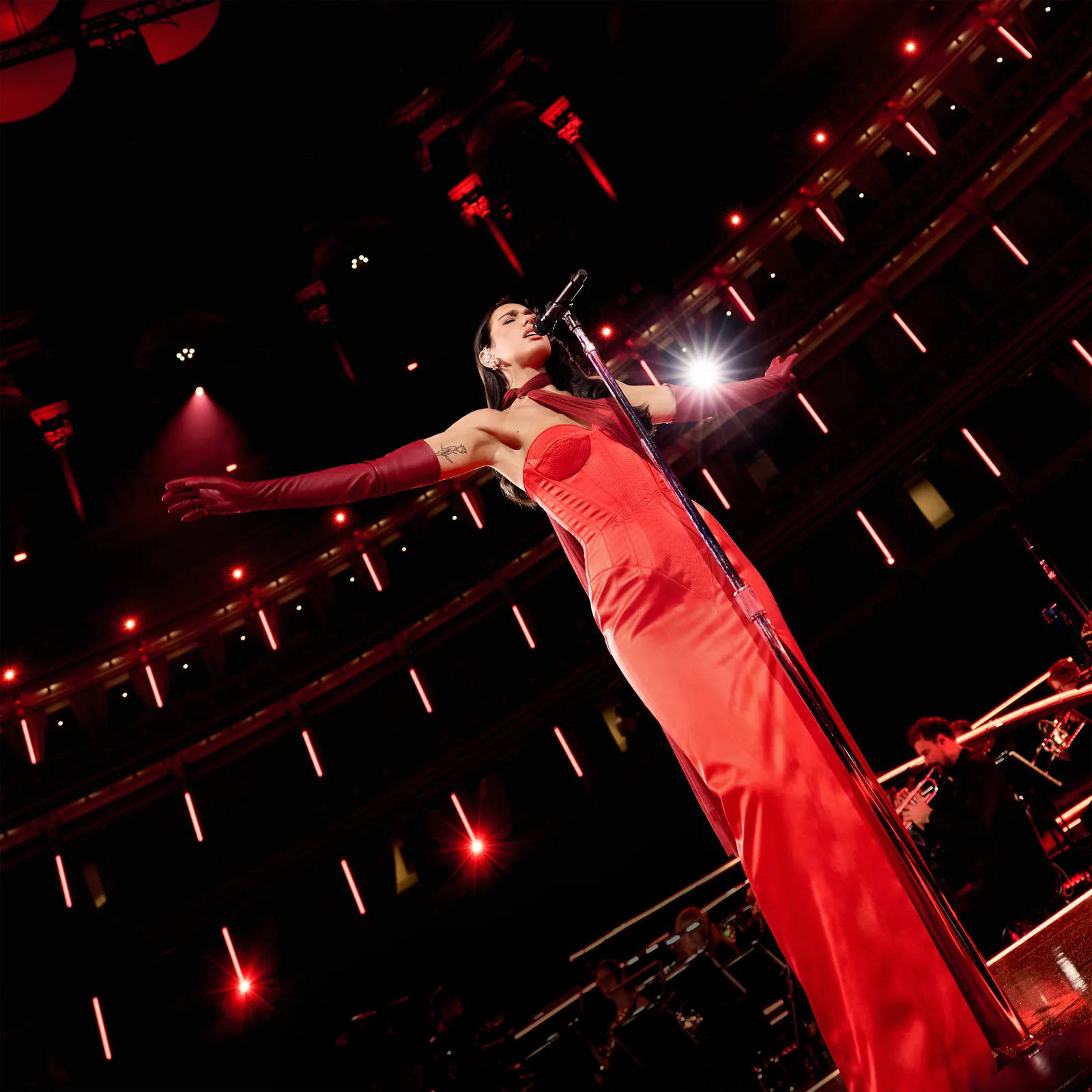 Dua Lipa on stage at the Royal Albert Hall performing live with an orchestra.