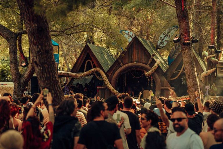 UNUM Festival 2026 main stage crowd dancing under pine trees at sunset with Ricardo Villalobos performing.
