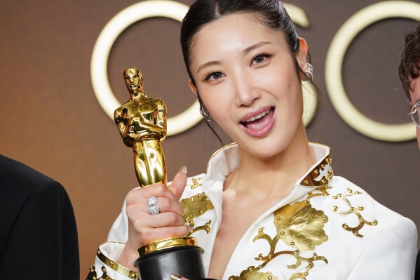 Teddy Park and the songwriting team of KPop Demon Hunters holding the Best Original Song Oscar trophy.
