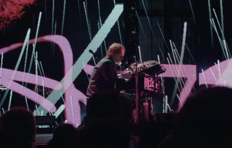 Thom Yorke performing solo at the Sydney Opera House with dramatic blue stage lighting.