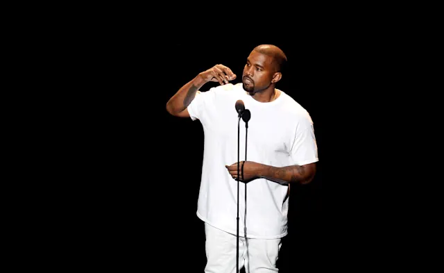 Kanye West performing live on a central rotating stage beneath a massive projection of the Earth at the Atatürk Olympic Stadium.